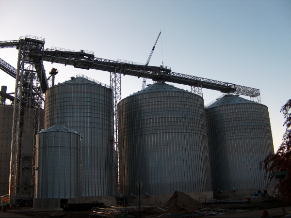 Three grain bins with the sun setting behind them