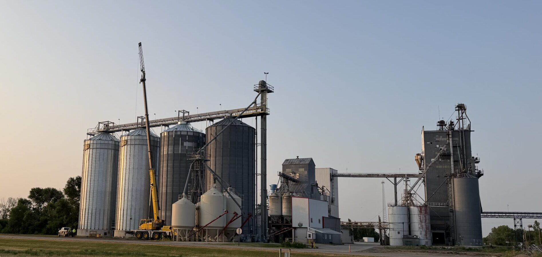 Grain system with a crane and the sun setting behind it